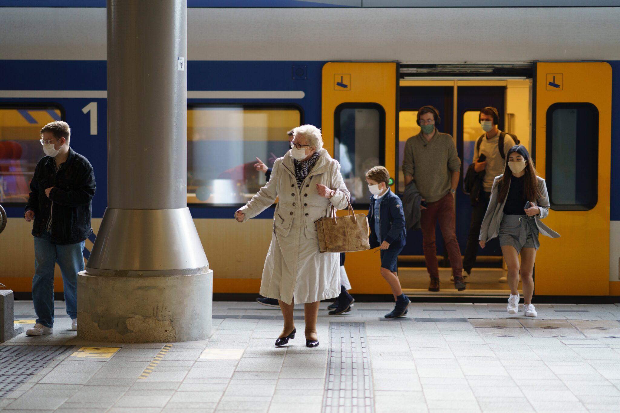 elderly lady in beige trenchcoat steps off the underground train